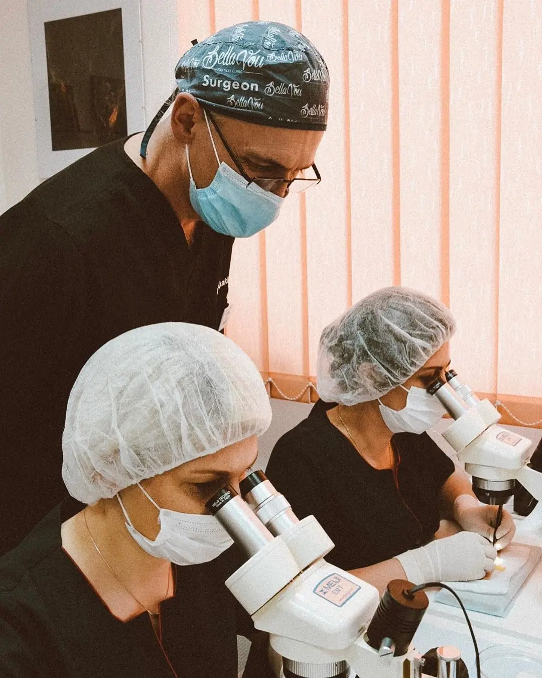Dr. Akaki Tsilosani supervising two trainee doctors working at stereo microscopes